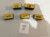 Straight-on view of five original Matchbox boxes showing front with car illustrations and model numbers 11, 39, 72, 73 and open yellow dune buggy