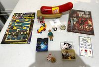 Full view of all vintage toy items on white cloth, showing Oscar Mayer Wienermobile, comic book, and assorted figurines and collectibles