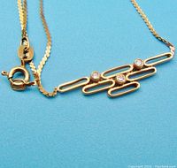 Close-up of pendant and clasp showing three bezel-set stones