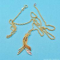 Chain and pendant laid out on blue background showing overall appearance