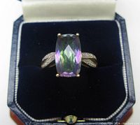 Front view of ring in box showing mystic topaz and split shoulders