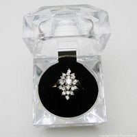 Ring displayed in clear acrylic case on black pad