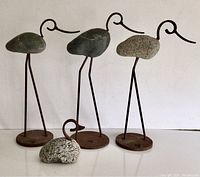 Front view of 4 iron and rock bird sculptures showing 3 cranes on iron bases and 1 smaller bird sculpture with rock body and iron neck/head