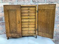 Chest interior with both doors open showing nine drawers and brass knobs