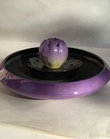 Image showing the assembled flower bowl with flower frog inserts (lily leaf and blossom) on top, highlighting the purple exterior and black interior.