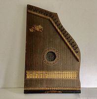 Full view of the antique wooden mandolin zither showing the strings, tuning pegs, and decorative sound hole.