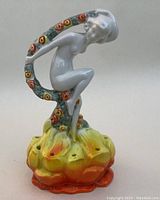 Front side view of the Art Deco porcelain flower frog showing the seated female figure and flower base with holes.