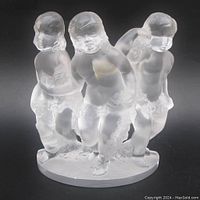 Front angled view of the frosted glass sculpture showing all three cherubs and the oval base.