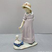 Full frontal view of the Lladro figurine showing the girl pulling the doll in the toy wagon.