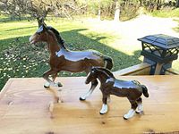Both horse figurines displayed on wooden surface outdoors