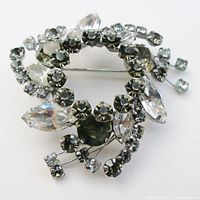 Clear and smoke rhinestone brooch shown from top view to highlight the arrangement of round and marquise cut stones and open center design.