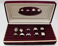 Set of ten silver rings arranged in red velvet jewelry box with a mirror on the interior lid.
