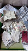Overview of assorted vintage linens including handkerchiefs, napkins with embroidery and lace.