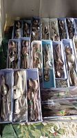 Multiple boxes of assorted vintage silver-tone flatware arranged on a surface, showing forks, spoons, and knives in various sizes and designs.