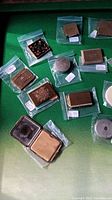 Overhead view of assorted vintage ladies compacts showing variety in shapes, materials and decorative patterns.
