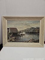 Full view of framed oil painting depicting harbor village with boats, seagulls and cottages