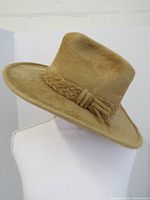Side angled view of large tan beaver fur felt Western cowboy hat with braided hatband.