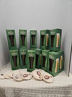 Full view of green Carlsberg packaging containing multiple beer glasses stacked, with Carlsberg branded beer coasters spread in front on a fabric surface.