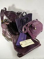 Full view of all items including Dr. Martens boots, four purple handbags, and a purple wallet.
