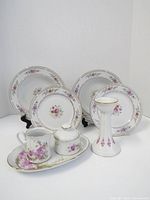 Image showing the full set of porcelain tableware including plates, tray, creamer, sugar bowl with lid, and candleholder with pink floral patterns and gold trim.