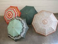 Four umbrellas laid out showing different colors and patterns, including floral and solid green.