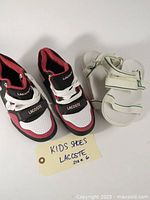 One pair of kids off-white/cream Lacoste sandals with adjustable Velcro straps and one pair of Lacoste sneakers size 6.
