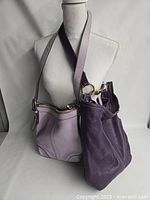 Two leather handbags displayed side by side, one lavender and one deep purple in color, showing overall shape and design