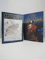 Two coffee table books, one titled 'Glen Loates: A Brush with Life' with a wildlife art cover, and the other titled 'Over Canada: Great Images, Great Adventure' with a mountain landscape cover.
