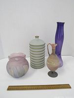 Four decorative glassware pieces displayed with ruler for scale