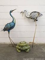 Set includes two metal bird sculptures with detailed feathers and a ceramic frog with speckled green-white finish.