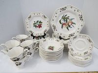 Full view of the full Nikko Classic Collection dinnerware set showing stacked plates, bowls, and 8 cups with octagonal shapes and fruit-floral pattern.