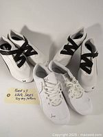 Three pairs of Puma white sneakers arranged together against a plain light background. Two pairs slip-on style with black zigzag straps and one pair lace-up style white sneakers with Puma logos visible.