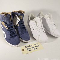 Two pairs of Reebok shoes displayed together: blue high top sneakers and white low top tennis shoes with a handwritten tag indicating high top and white tennis.