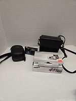 Photo showing the digital camera, original box, two carrying bags, and manual arranged on a white surface.