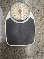 Top view of Taylor mechanical bathroom scale showing white body and black textured stepping platform.