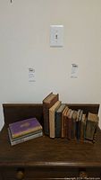 Full view of the antique and vintage books arranged between wooden bookends on a wooden surface