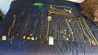 Top view of costume jewelry collection laid out on dark fabric showing a variety of necklaces and bracelets including some with pendants and beads.