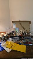 Wide view showing assortment of costume jewelry, gift bags, and decorative box on wood surface.