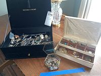 Overview photo showing three jewelry storage units on wood table with assorted jewelry pieces inside