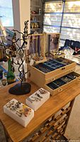 Overview of metal display tree, jewelry box, foam earring holders and loose bracelets on table