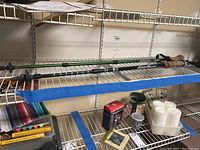 Two adjustable hiking poles, one Eddie Bauer and one Wilcor, placed on storage shelves with other household items.
