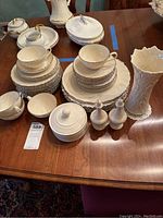Full view of Lenox Weatherly china set including plates, bowls, cups, covered candy dish, salt and pepper shakers, butter dish, and tall vase arranged on wooden table.