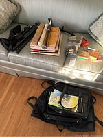 Full overview of all lot contents including music books, reeds, instrument bags, music stand, and small accessories arranged on a sofa and floor.