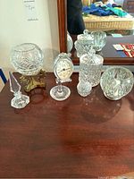 Full set of Polish crystal items displayed on a wooden surface in front of a mirror: two crystal bowls, crystal ring holder, covered container, small covered dish, and a crystal clock with metal base.
