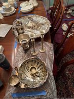 Photo showing all items together on table with several silver plated objects including candlesticks, serving tray, and carafe with warmer stand.