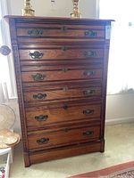 Front view of vintage chest of drawers showing six drawers with ornate metal handles and keyholes.