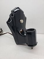 Side view of black glossy ceramic wall sconce with angular Art Deco design and bulb holder.