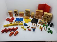 Photo showing all wooden town blocks arranged, including building facades, roof pieces, people figures, vehicles, and trees