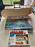 Photo showing the open Hot Wheels Service Center playset with ramps and sign on display, with Power Blocks and LOC Blocs boxes in front.