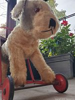 Close up of stuffed dog's face and front wheels showing plush fur and wheel detail